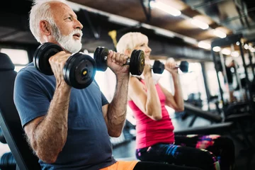 Fototapeten Fit älteres sportliches Paar, das zusammen im Fitnessstudio trainiert © NDABCREATIVITY