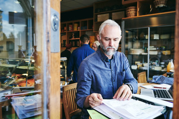 sales clerk reading documents while sitting at table in store