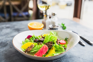 Tasty salad with citrus, lettuce and chicken liver with glass of vine. Healthy food