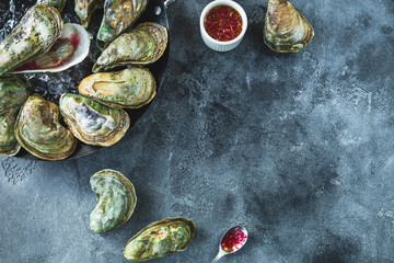 Raw ocean oysters with glass of white wine and limes on dark table. Flat lay. Top view. Food background