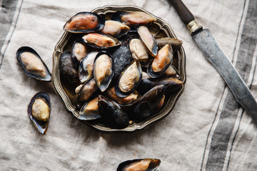 Frozen mussels in metallic vintage plate on linen tablecloth with stripes