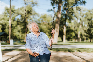 Happy senior woman listening to music on a swing