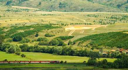 Bulgaria beautiful colorful meadow landscape, summertime, mountain train. Bulgarian  narrow-gauge railway train.
