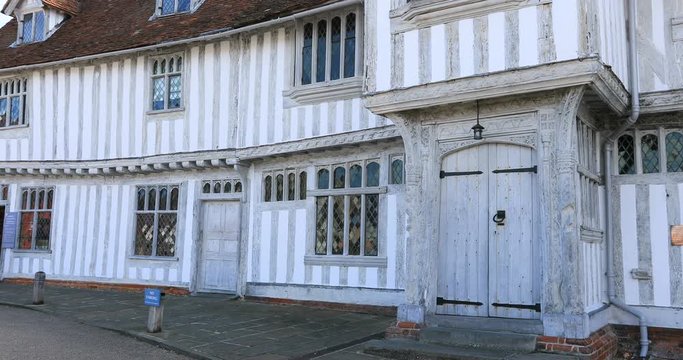 Lavenham England Guild Hall historic village man walks. Lavenham village, civil parish in Suffolk, England. 15th century church, half timbered crooked unlevel medieval cottages and business.