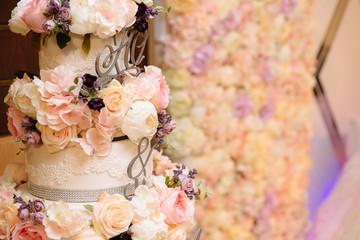 Close-up multilevel wedding cake decorated with flowers stands on a table. Concept of eating, sweets and desserts at a party.