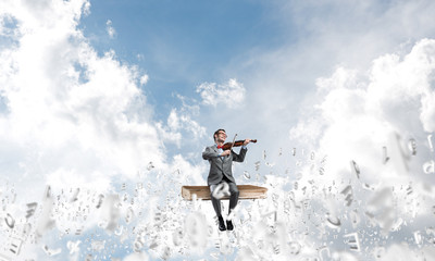 Handsome violinist play his melody and symbols fly around in air