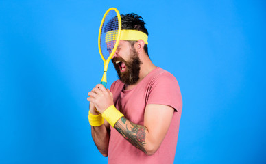 Man bearded hipster wear old school sport outfit with bandages. Tennis player retro fashion. Tennis sport and entertainment. Athlete hold tennis racket in hand on blue background. Tennis club concept