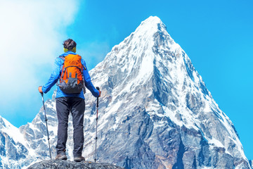 Hiker with backpacks reaches the summit of mountain peak. Success, freedom and happiness, achievement in mountains. Active sport concept.