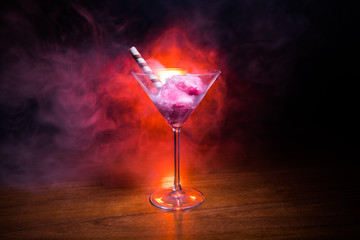 Martini glass filled with colorful fruit ice cream on dark background with toned light and fog