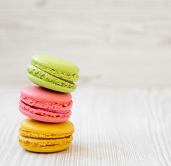 Stack of colorful macaroons on a white wooden background, side view. Space for text.