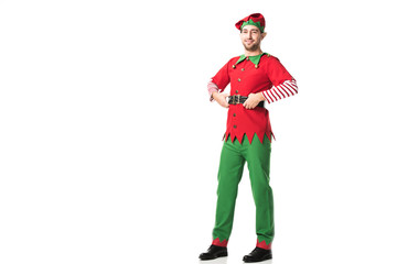 smiling man in christmas elf costume looking at camera with hands on hips isolated on white