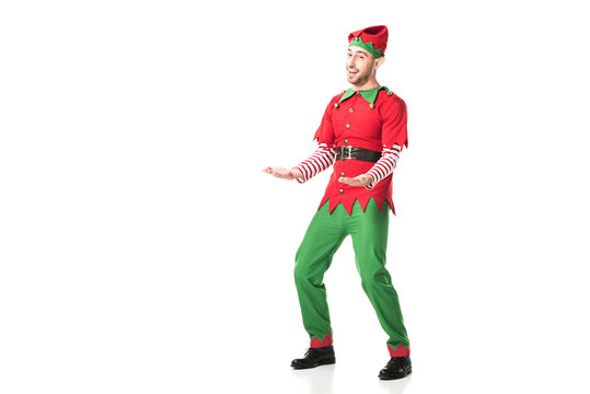 cheerful man in christmas elf costume outstreching hands in excitement isolated on white