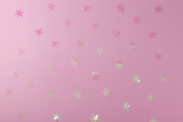 A gentle transparent white snowflake on a light pink background. Flat Lay layout of New Year's decorations and confetti sequins.