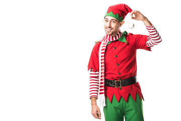 smiling man in christmas elf costume holding bauble and looking at camera isolated on white