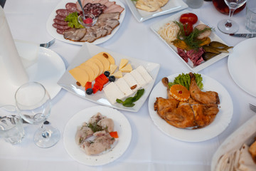 The served festive table is covered with a white tablecloth with dishes and drinks with glasses in the ceremonial hall