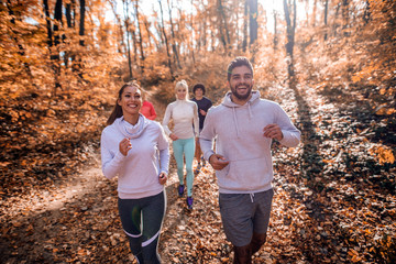Small group of people running in woods.