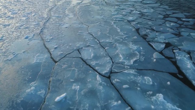 Frozen winter sea melting and ice floes drifting with waves aerial shot