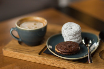 Cup of coffee with cookie and zephyr dessert on wooden board