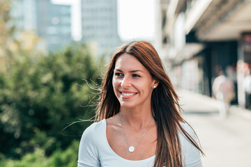 Portrait of a smiling young woman walking in the city. Close-up.