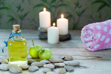 Fototapeta na wymiar bottle of apple oil massage, river pebbles and two small green apples