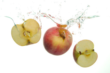 Red Apple and and two aple slices splash in water on white