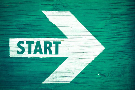 Start Text Written On White Directional Arrow Pointing Right Painted On A Green Wooden Signboard Background. Motivation Concept For Start Line For Business Begin And Professional Career Path.