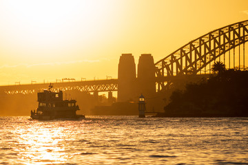 Obraz premium Sunset on Sydney Harbour with a famous Sydney Ferry and the Harbour Bridge as a backdrop.