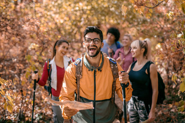 Man holding map and leading group of people while walking in woods.