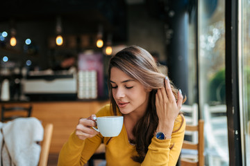 Stylish young woman drinking coffee at the cafe.
