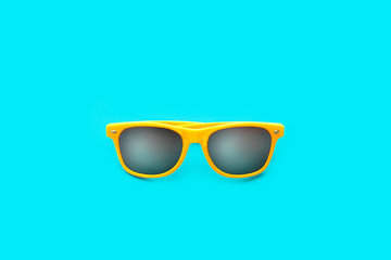 Yellow sunglasses in intense cyan blue large background. Minimal image concept for ready for summer, sun protection, hot days and tropical travel vacation.