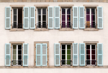 Fototapeta na wymiar Eight windows with shutters open and closed on a building in France