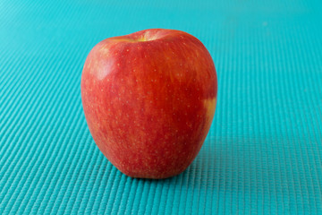 Red apple on sky blue texture surface