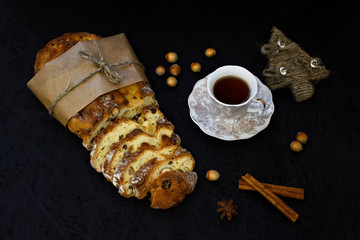 Traditional German Christmas pastry - stollen on a black background with fir branches, spices and Christmas decorations