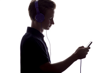 silhouette of boy in headphones flipping playlist of music on a white isolated background