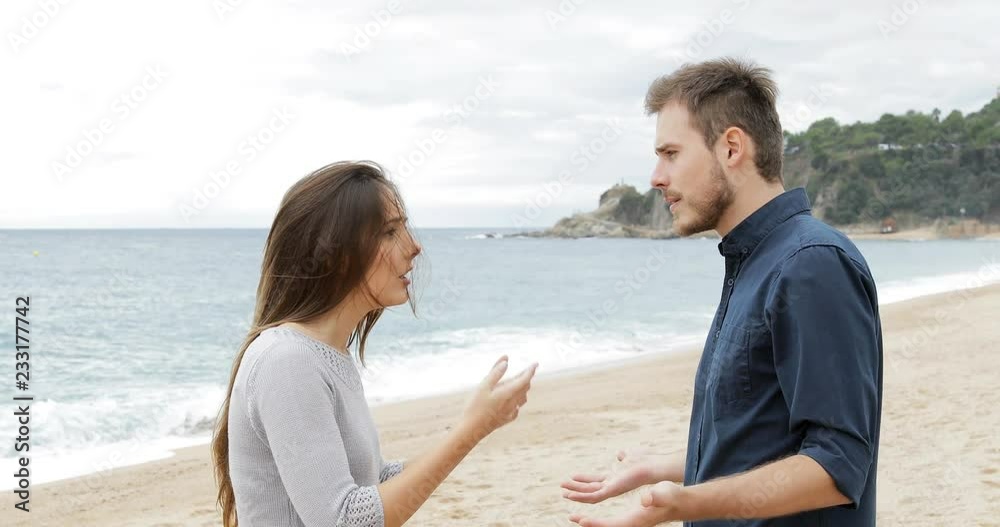 Wall mural Angry couple breaking up after argument on the beach. Girlfriend leaves her sad boyfriend