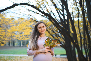 Pretty Pregnant Woman with Autumn Leaves