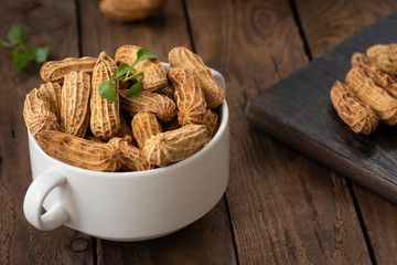 peanuts in white bowl on wood


