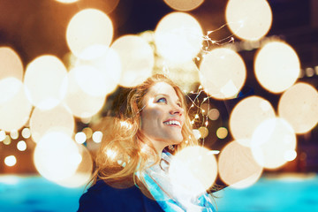 Happy young woman amazed by LED fairy lights at city outdoor