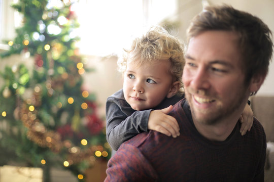 Sweet dad playing with his son in front of the christmas tree