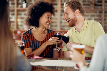 Friends making a toast while sitting in restaurant. Multi-ethnic group.