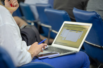 Woman sitting on a couch with a laptop on her knees, working. Writing on her blog, typing messages in social media. Soft light, indoors
