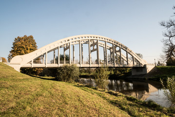 white concrete bridge over Olse river with colorful tree on the background and clear sky in Karvina city in Czech republic