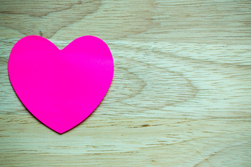 Pink stick note isolated on wood background.paper heart shape on wood texture with copy space. Image for Valentines day.symbol of love. use to greeting card and background.horizontal.