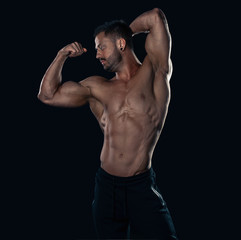 Obraz na płótnie Canvas Brutal strong bodybuilder athletic man posing on black background.