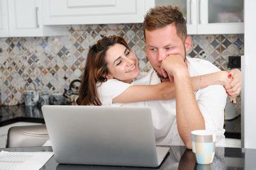 happy smiling pretty young woman embracing pensive upset man with laptop kitchen