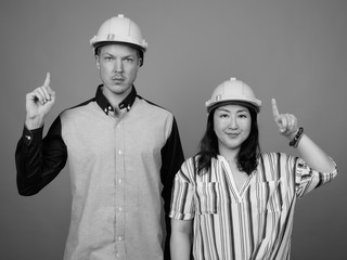 Businessman and mature Asian businesswoman wearing hardhat