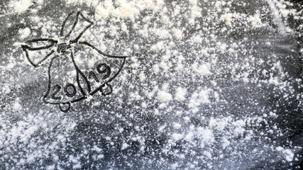 Christmas bells with bow made from flour on black wooden background, number 2019.