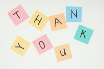 colorful sticky notes spelling thank you on lace with clothespins isolated on white background