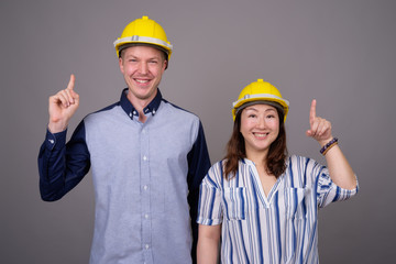 Businessman and mature Asian businesswoman wearing hardhat