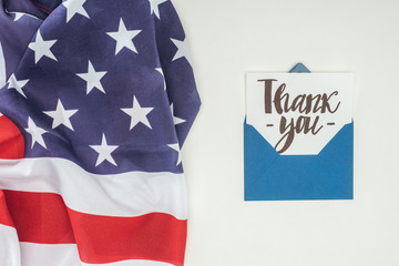 thank you lettering sticking out of blue envelope with american flag isolated on white background